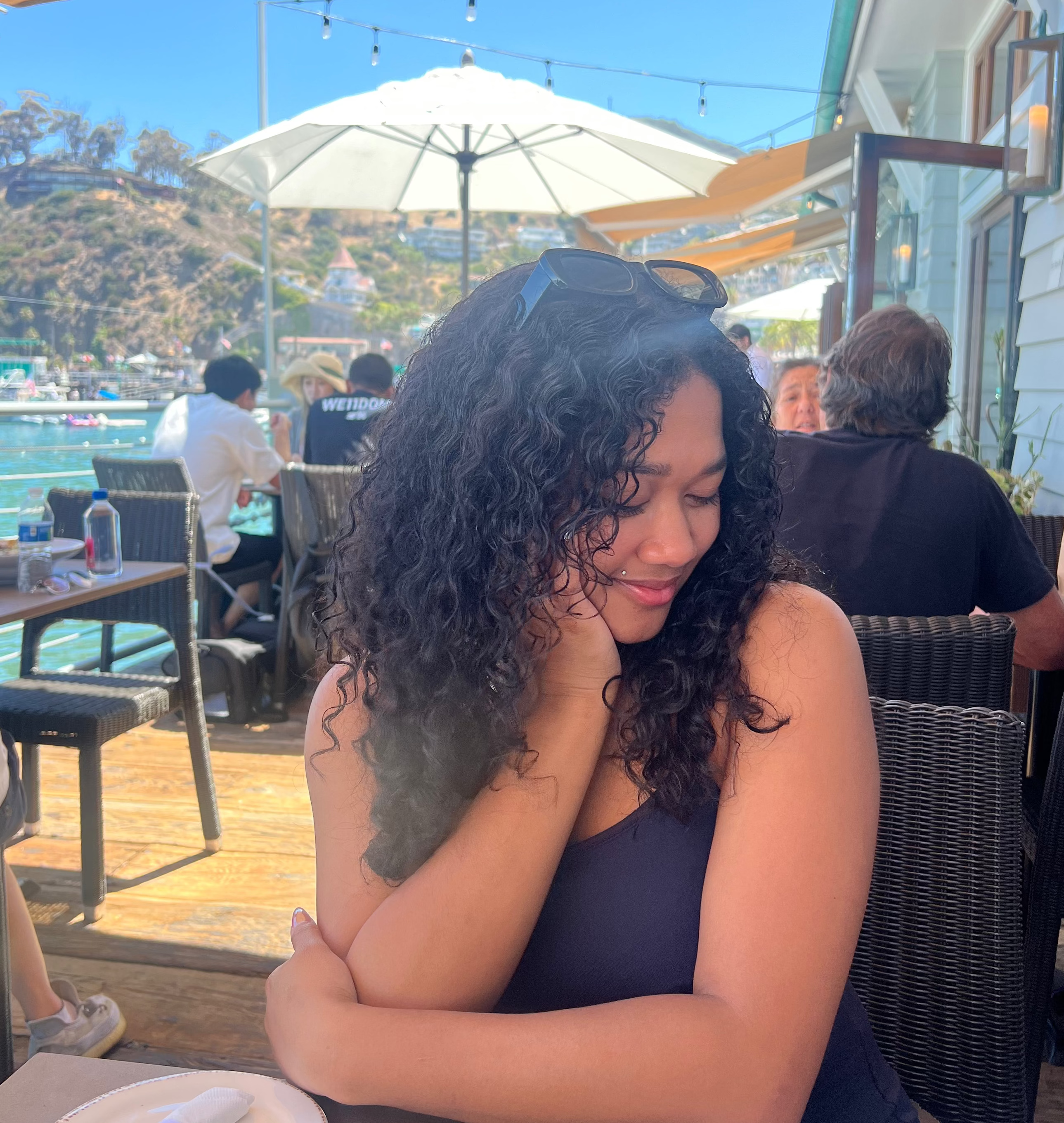 woman sitting at an outdoor cafe table with a scenic background
