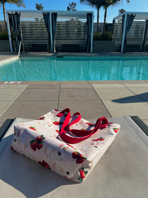 Product image. Tote with strawberries and bunnies near a pool.
